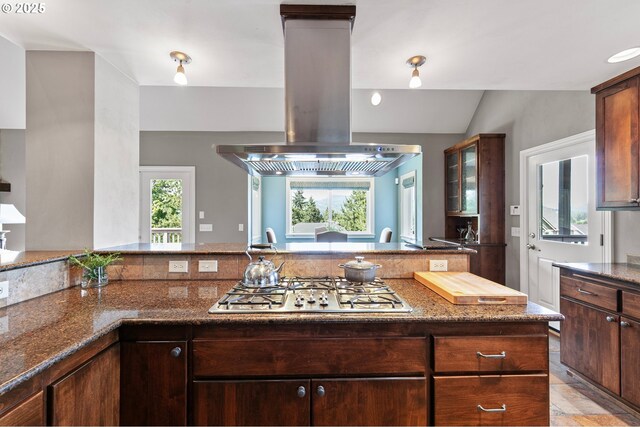 380 Mountaingate Dr, Springfield, OR 97478 - kitchen featuring island range hood, stainless steel gas stovetop, dark stone counters, glass insert cabinets, and dark brown cabinetry