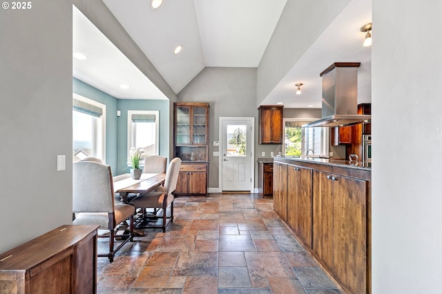 380 Mountaingate Dr, Springfield, OR 97478 - kitchen with stone tile floors, plenty of natural light, brown cabinets, vaulted ceiling, and island exhaust hood