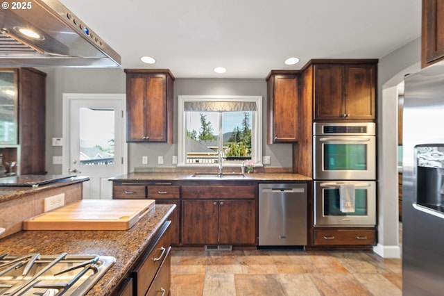 380 Mountaingate Dr, Springfield, OR 97478 - kitchen featuring appliances with stainless steel finishes, exhaust hood, recessed lighting, light stone finish flooring, and dark stone countertops