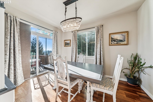 dining area featuring dark wood-type flooring and a notable chandelier