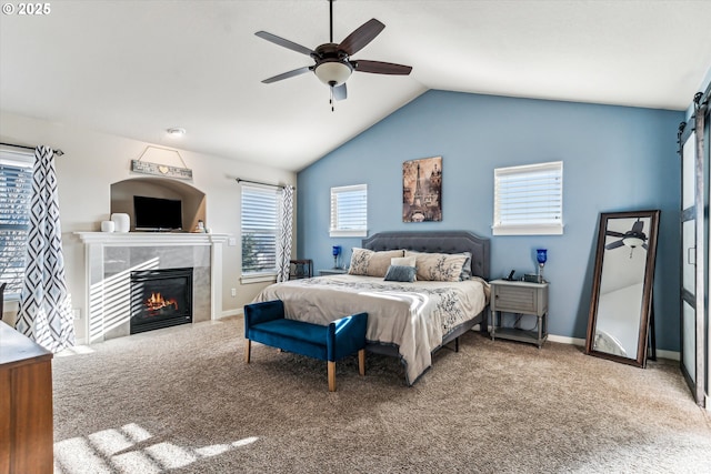 carpeted bedroom with a tiled fireplace, vaulted ceiling, and ceiling fan