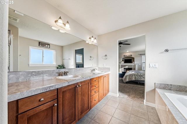 bathroom featuring vanity, a relaxing tiled tub, tile patterned floors, and ceiling fan