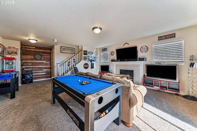 rec room featuring a fireplace, wooden walls, carpet, and a textured ceiling