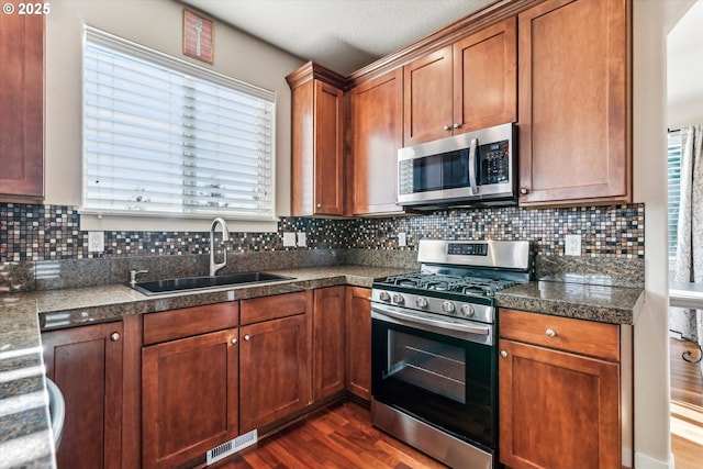 kitchen featuring dark hardwood / wood-style flooring, sink, backsplash, and stainless steel appliances