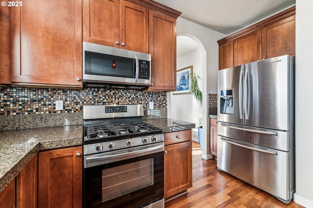 kitchen with tasteful backsplash, appliances with stainless steel finishes, and hardwood / wood-style flooring