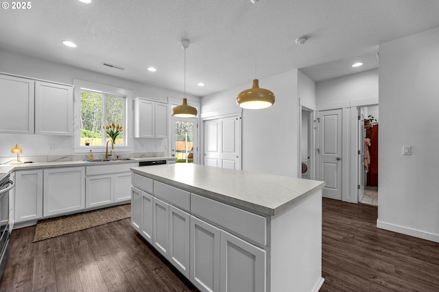 kitchen featuring dark wood-style floors, a sink, visible vents, white cabinetry, and light countertops