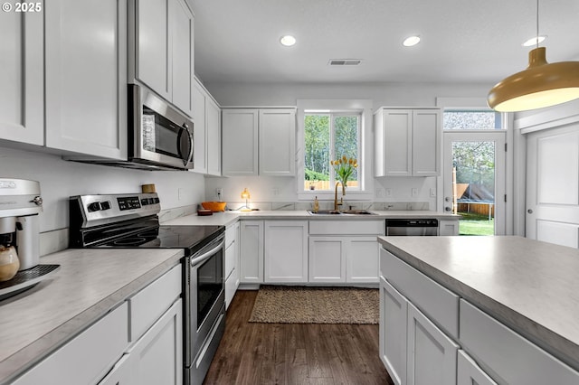 kitchen with stainless steel appliances, a sink, visible vents, recessed lighting, and dark wood-type flooring