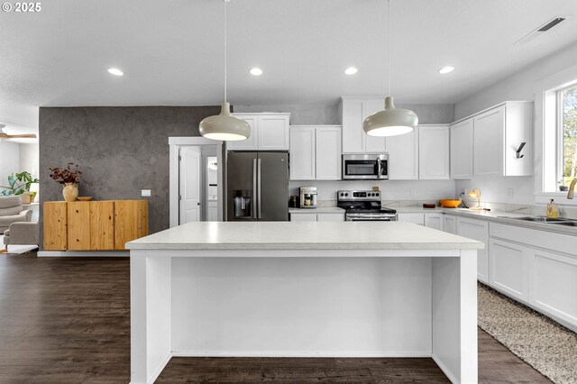 kitchen featuring dark wood-style floors, light countertops, visible vents, a kitchen island, and appliances with stainless steel finishes