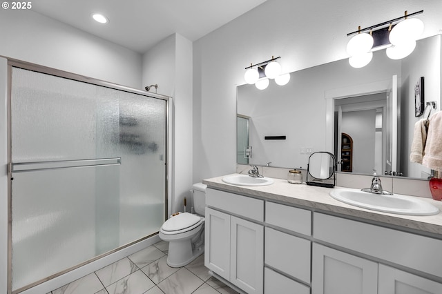 full bath featuring a sink, a shower stall, double vanity, and toilet