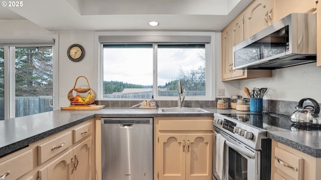 kitchen featuring appliances with stainless steel finishes, dark countertops, a sink, and recessed lighting