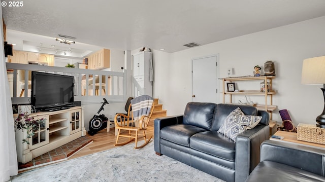 living room with visible vents, stairway, and wood finished floors