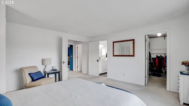 bedroom featuring a closet, light colored carpet, connected bathroom, and a spacious closet