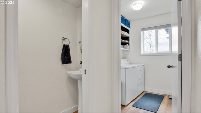 half bathroom featuring baseboards, wood finished floors, and washing machine and clothes dryer