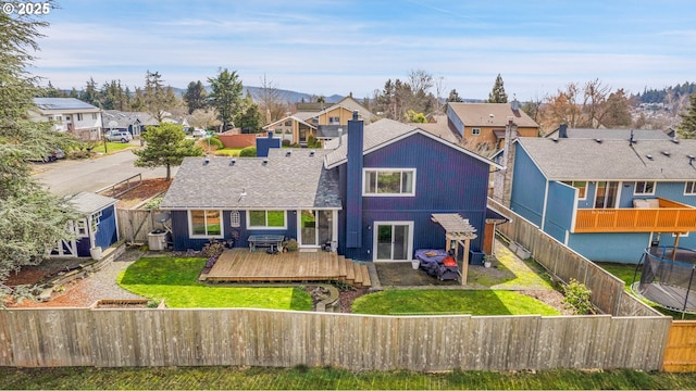 back of house featuring a fenced backyard, a residential view, a deck, and a yard