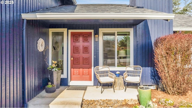 doorway to property featuring a shingled roof and covered porch