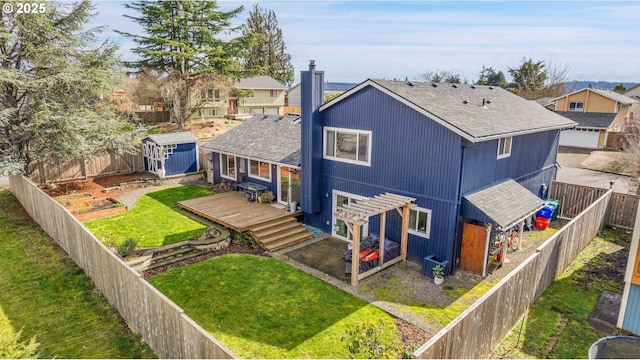 back of house featuring a fenced backyard, a chimney, an outbuilding, a storage unit, and a deck