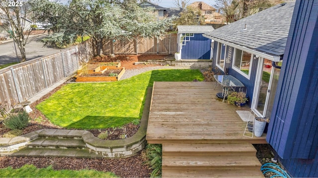 view of yard featuring an outbuilding, a vegetable garden, a shed, a fenced backyard, and a wooden deck