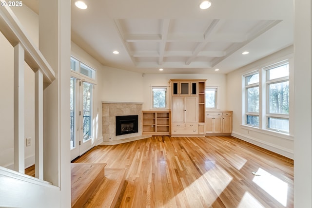 unfurnished living room with coffered ceiling, a fireplace, beam ceiling, and light hardwood / wood-style floors