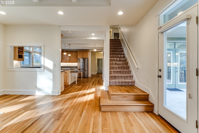 stairway with beamed ceiling, plenty of natural light, and hardwood / wood-style floors