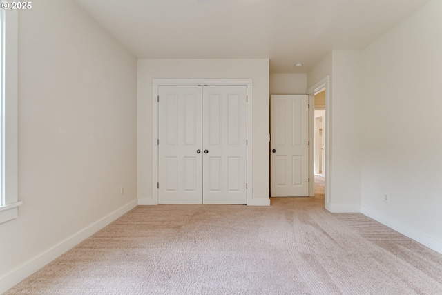 unfurnished bedroom with light colored carpet and a closet