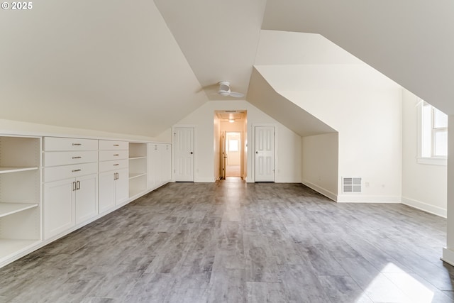 additional living space featuring lofted ceiling and light wood-type flooring