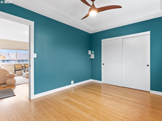 unfurnished bedroom featuring ceiling fan, a closet, and light hardwood / wood-style flooring