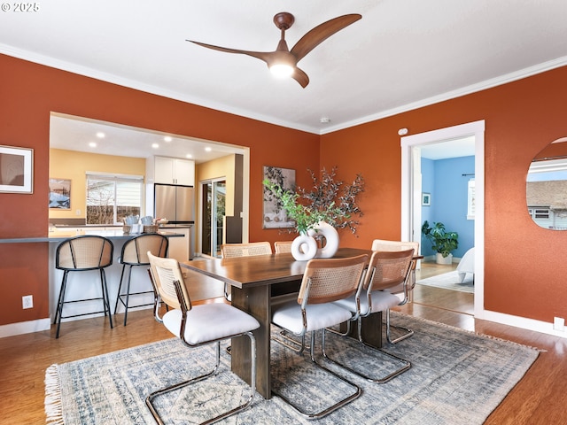 dining space with hardwood / wood-style floors, ornamental molding, and ceiling fan