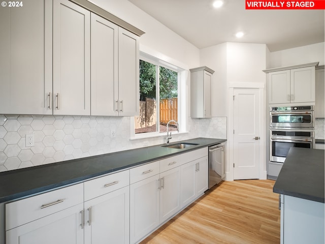 13906 SW 165th Ave, Tigard, OR 97223 - kitchen with a sink, stainless steel appliances, dark countertops, decorative backsplash, and light wood-style flooring