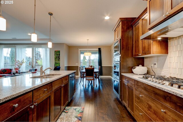 kitchen with pendant lighting, sink, dark wood-type flooring, appliances with stainless steel finishes, and light stone counters