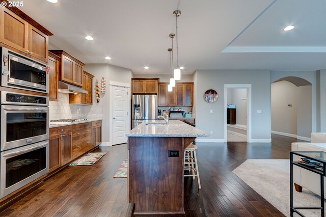 kitchen featuring pendant lighting, sink, appliances with stainless steel finishes, a kitchen island with sink, and a kitchen breakfast bar