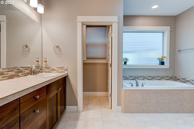 bathroom featuring tile patterned flooring, tiled tub, decorative backsplash, and vanity