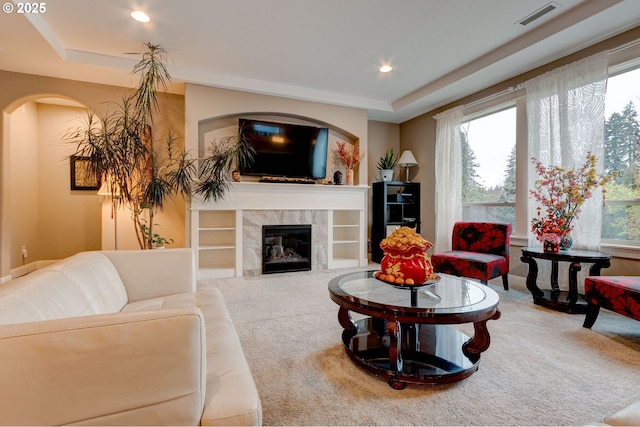 living room with a tray ceiling, a fireplace, and carpet