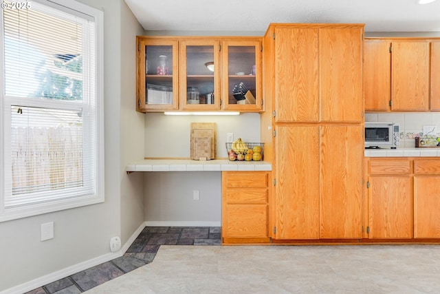 4870 Dorrance Loop NE, Salem, OR 97305 - kitchen featuring built in desk, white microwave, glass insert cabinets, and tile counters