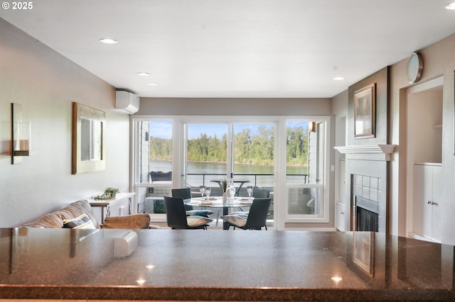 living area with an AC wall unit, healthy amount of natural light, a fireplace, recessed lighting, and a water view