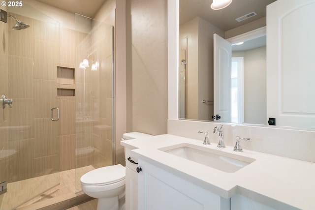 bathroom featuring vanity, toilet, and a shower with shower door