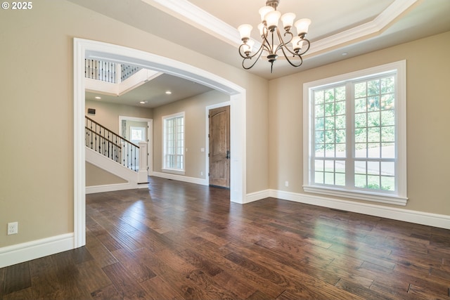 spare room with crown molding, dark hardwood / wood-style floors, an inviting chandelier, and a tray ceiling