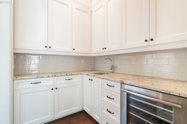 kitchen featuring white cabinetry, sink, wine cooler, and light stone counters