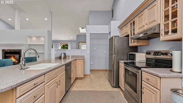 35130 Ponderosa Loop, Manzanita, OR 97130 - kitchen with appliances with stainless steel finishes, under cabinet range hood, light tile patterned floors, a premium fireplace, and glass insert cabinets
