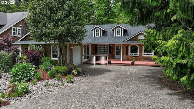 35130 Ponderosa Loop, Manzanita, OR 97130 - cape cod-style house with covered porch, driveway, an attached garage, and a shingled roof