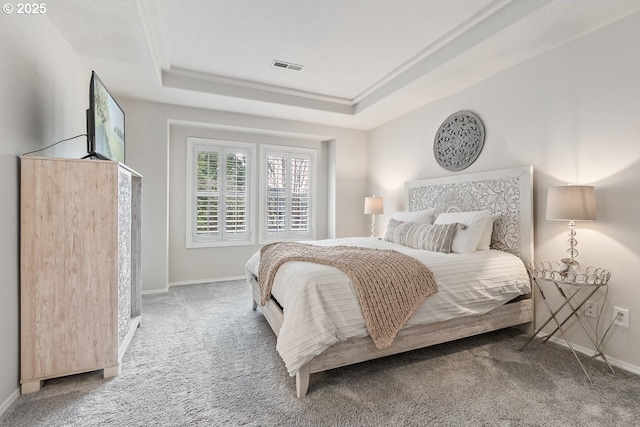 carpeted bedroom with visible vents, a tray ceiling, and baseboards