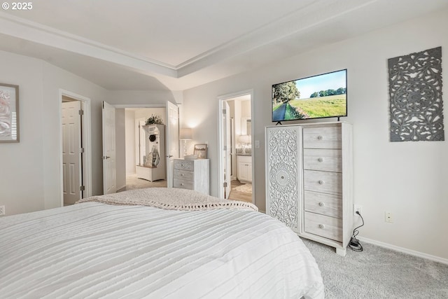 bedroom with baseboards, connected bathroom, and light colored carpet