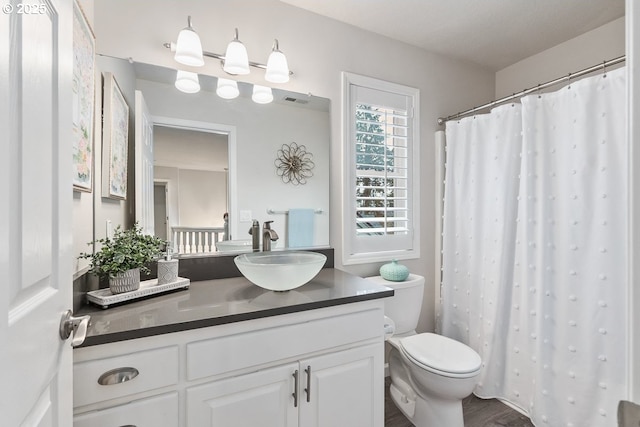 bathroom with toilet, curtained shower, visible vents, and vanity