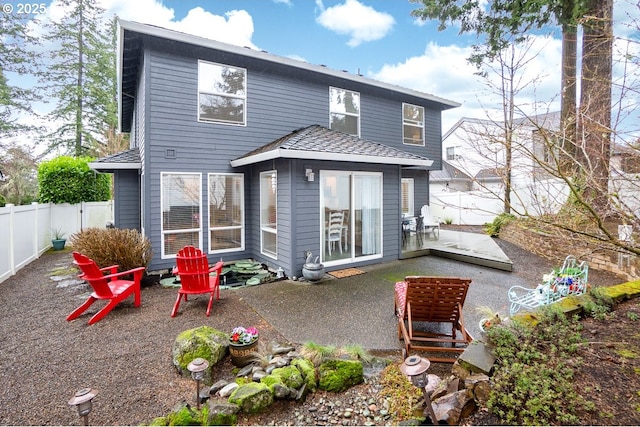 rear view of property featuring a shingled roof, a patio area, and a fenced backyard