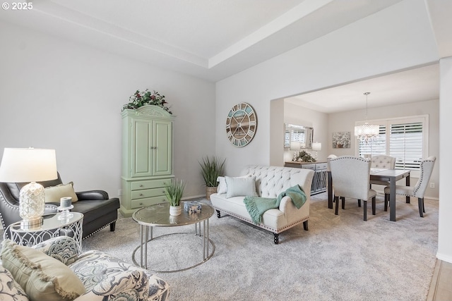 living area featuring light carpet, an inviting chandelier, and baseboards