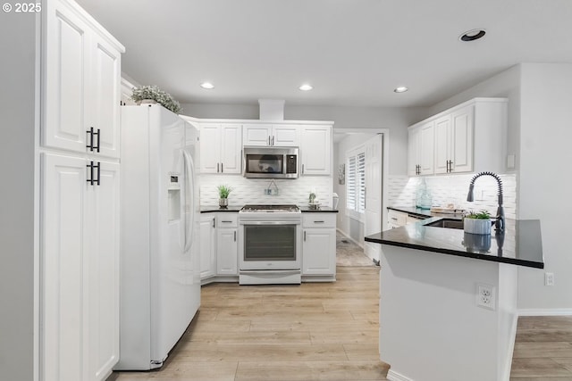 kitchen with range with gas stovetop, dark countertops, stainless steel microwave, white fridge with ice dispenser, and a sink