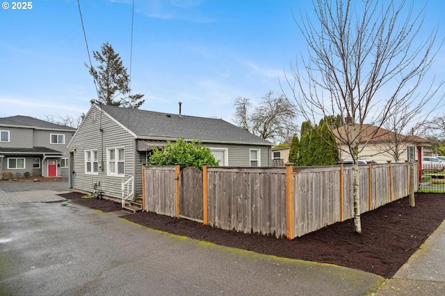 view of front facade with a shingled roof and fence