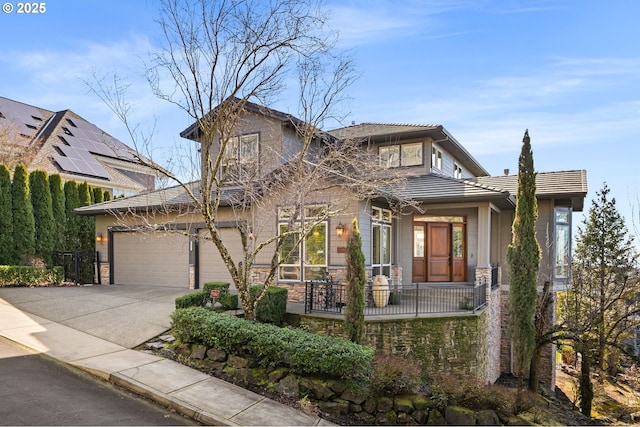 view of front facade featuring driveway, stone siding, and a tiled roof