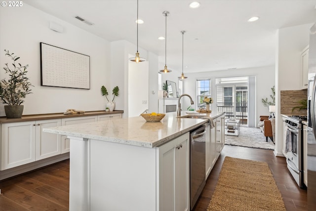 kitchen with appliances with stainless steel finishes, a sink, dark wood-type flooring, white cabinetry, and recessed lighting