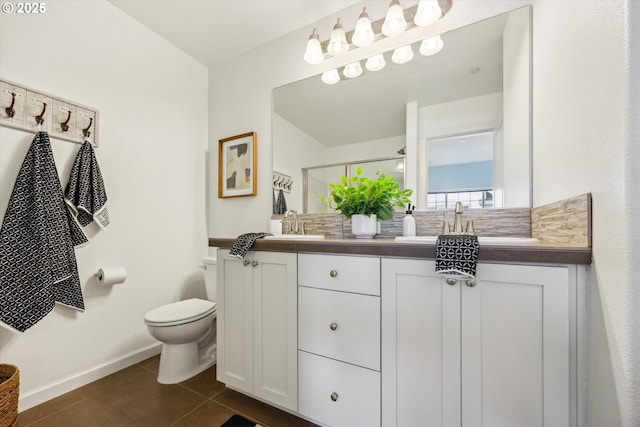 full bath featuring toilet, tile patterned floors, baseboards, double vanity, and a shower with shower door