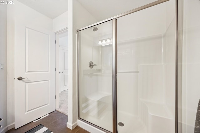 bathroom with a stall shower, tile patterned floors, and baseboards